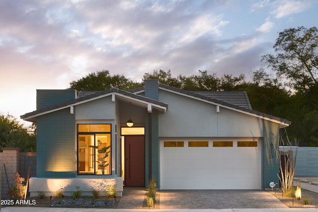 view of front of house with a garage, decorative driveway, and stucco siding