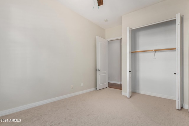 unfurnished bedroom with ceiling fan, a closet, and light carpet