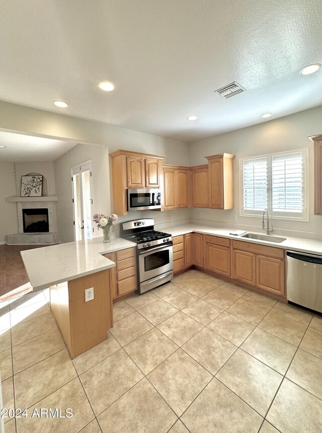 kitchen with sink, light tile patterned floors, a breakfast bar, appliances with stainless steel finishes, and kitchen peninsula