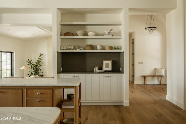 bar featuring light hardwood / wood-style floors, built in features, and hanging light fixtures