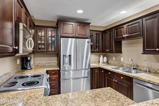 4200 N Miller Rd Unit 408, Scottsdale, AZ 85251 - kitchen with appliances with stainless steel finishes, dark brown cabinets, glass insert cabinets, recessed lighting, and light stone counters