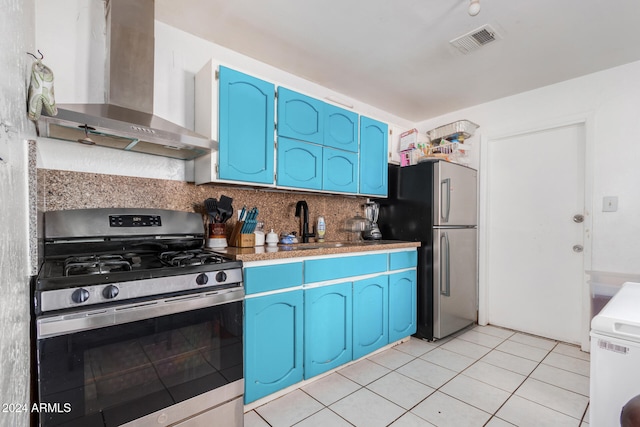 kitchen with appliances with stainless steel finishes, backsplash, blue cabinets, wall chimney range hood, and light tile patterned floors