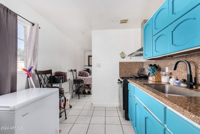 kitchen featuring black range with gas stovetop, blue cabinets, fridge, and sink