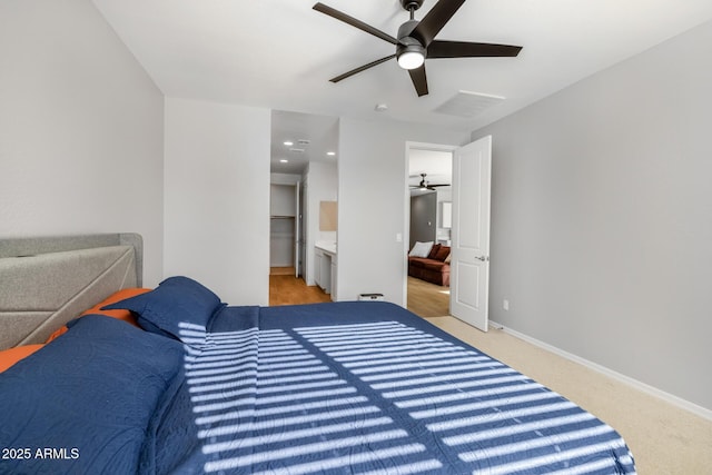 bedroom with ceiling fan, light colored carpet, and ensuite bathroom