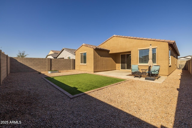 rear view of property featuring a lawn, a patio, and a fire pit