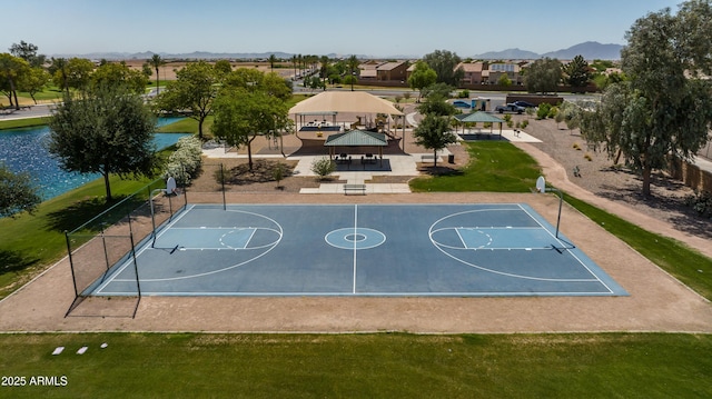 view of sport court featuring a gazebo, a water and mountain view, and a lawn