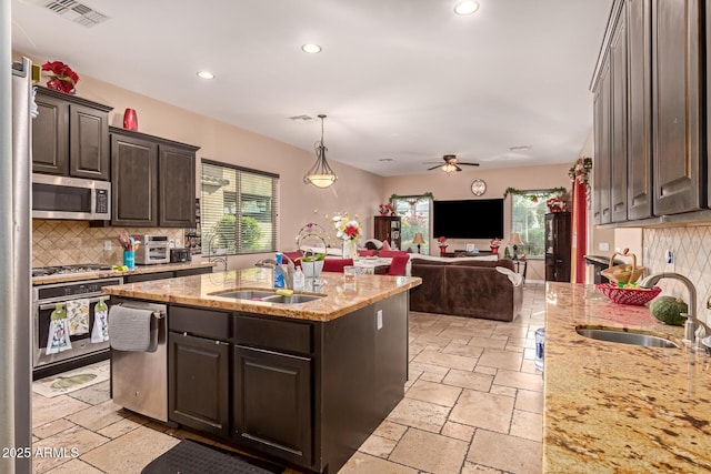 kitchen with dark brown cabinetry, stainless steel appliances, a center island with sink, and sink