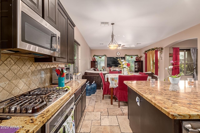 kitchen featuring appliances with stainless steel finishes, backsplash, dark brown cabinets, and pendant lighting