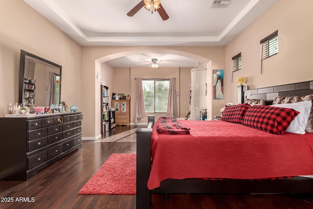 bedroom with ceiling fan, a raised ceiling, and dark wood-type flooring