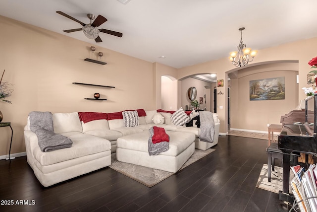 living room with dark hardwood / wood-style flooring and ceiling fan with notable chandelier