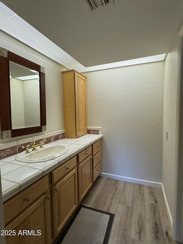 bathroom with visible vents, baseboards, wood finished floors, and vanity