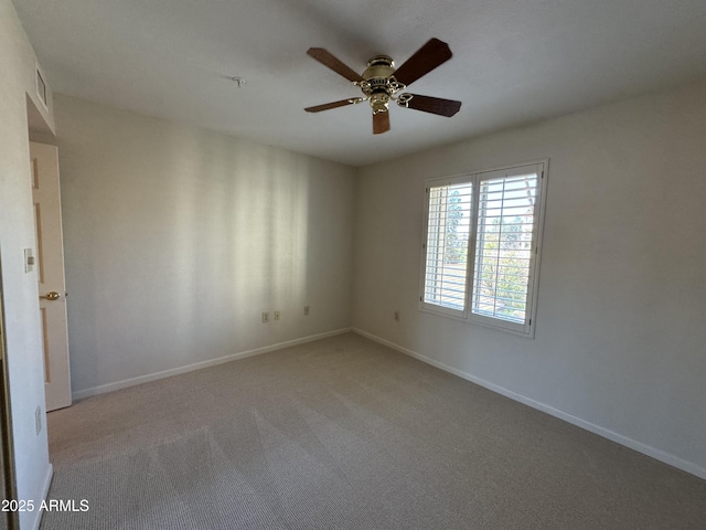 empty room featuring visible vents, light colored carpet, baseboards, and a ceiling fan