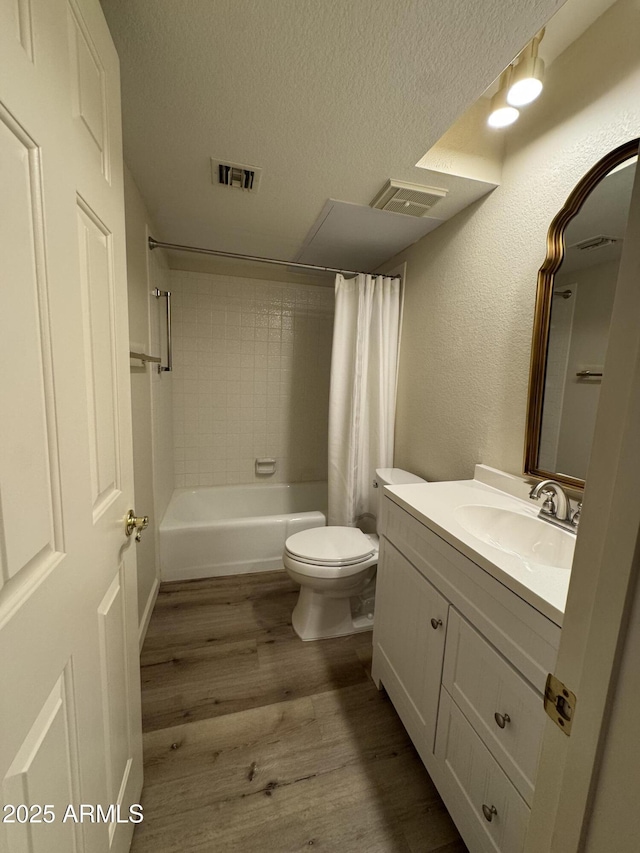 bathroom with vanity, wood finished floors, visible vents, a textured ceiling, and toilet