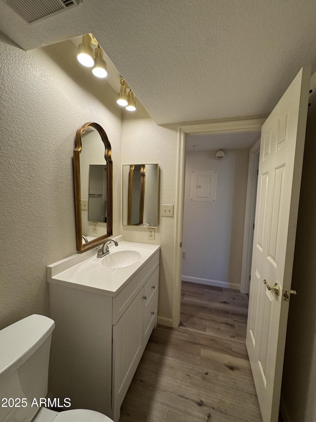 bathroom featuring visible vents, toilet, a textured ceiling, and a textured wall