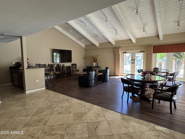 dining space with light tile patterned floors, baseboards, beam ceiling, rail lighting, and french doors