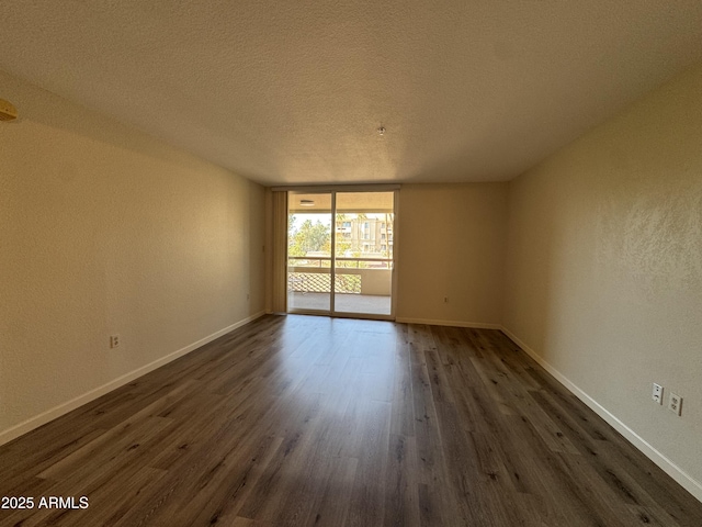 unfurnished room with dark wood finished floors, a wall of windows, and baseboards