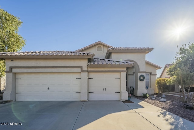 mediterranean / spanish-style home featuring driveway, a tiled roof, an attached garage, and stucco siding