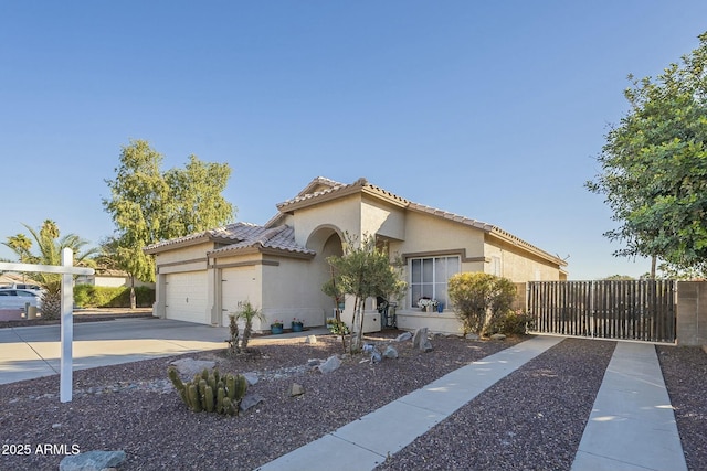 mediterranean / spanish-style home featuring a garage, concrete driveway, a tiled roof, and stucco siding