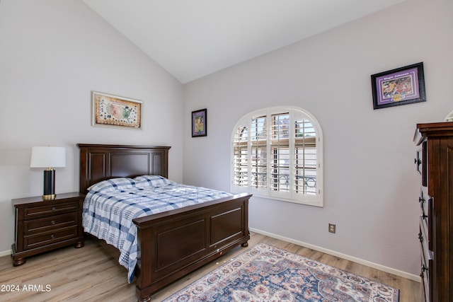 bedroom featuring lofted ceiling, baseboards, and light wood-type flooring