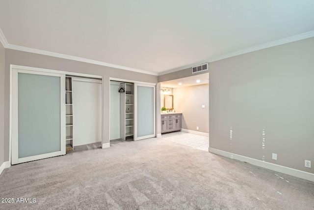 unfurnished bedroom featuring multiple closets, light colored carpet, connected bathroom, and ornamental molding