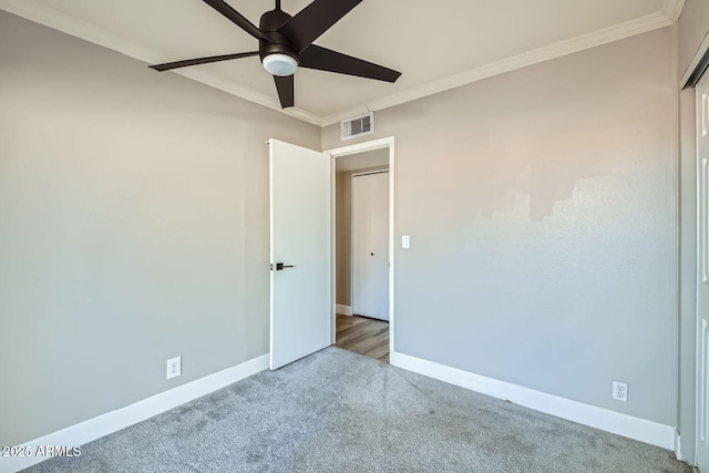 carpeted spare room with ceiling fan and ornamental molding