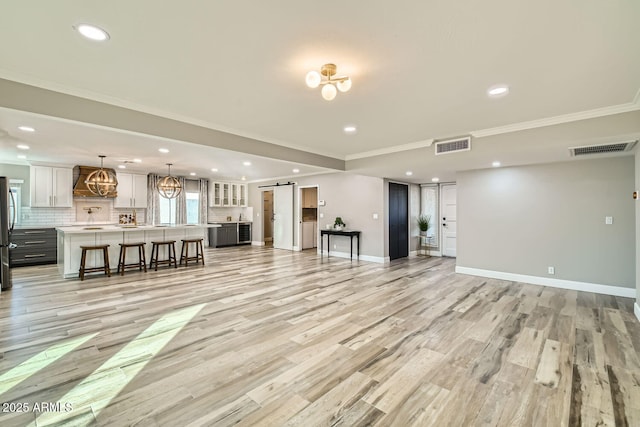 unfurnished living room featuring ornamental molding, light wood-type flooring, and a barn door