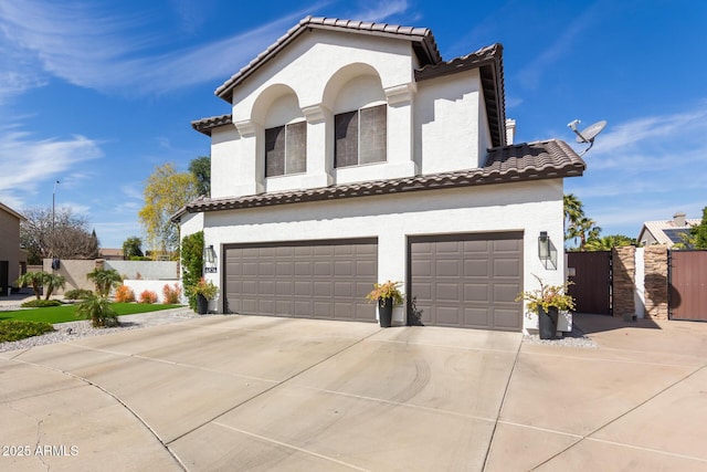 mediterranean / spanish home with a garage, a tile roof, and stucco siding