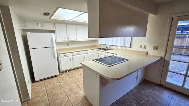 kitchen featuring white cabinetry, white refrigerator, kitchen peninsula, black cooktop, and light tile patterned flooring