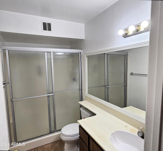 bathroom with toilet, vanity, tile patterned floors, and an enclosed shower