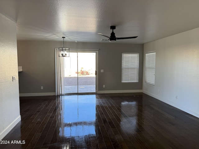 unfurnished room with dark hardwood / wood-style flooring, ceiling fan with notable chandelier, and a textured ceiling