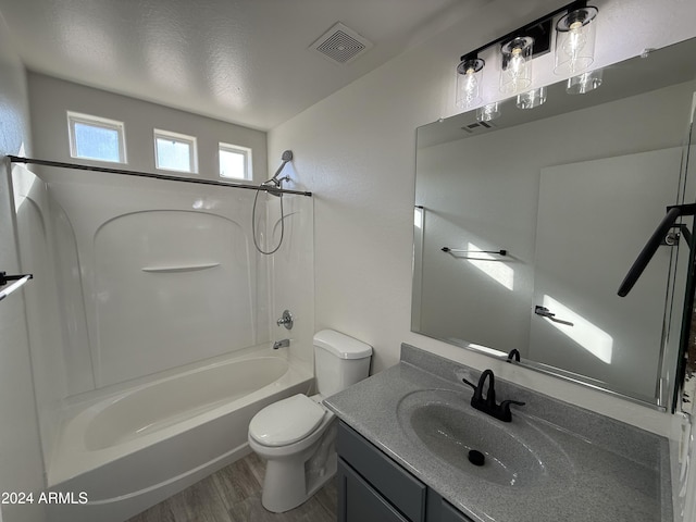 full bathroom featuring hardwood / wood-style floors, vanity, a textured ceiling, shower / washtub combination, and toilet