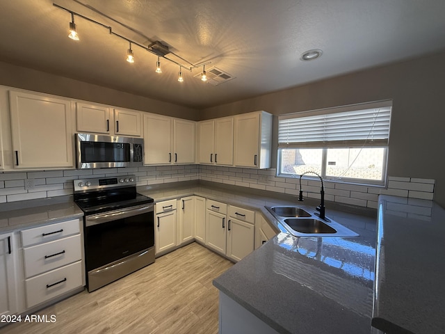 kitchen with white cabinetry, sink, decorative backsplash, and stainless steel appliances