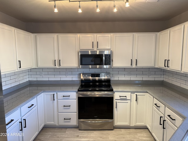 kitchen with tasteful backsplash, white cabinetry, and appliances with stainless steel finishes