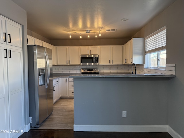 kitchen with stainless steel appliances, white cabinets, dark hardwood / wood-style flooring, decorative backsplash, and kitchen peninsula