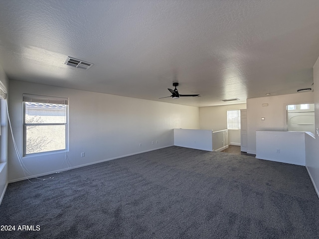 unfurnished room with ceiling fan, washer / dryer, a textured ceiling, and dark colored carpet