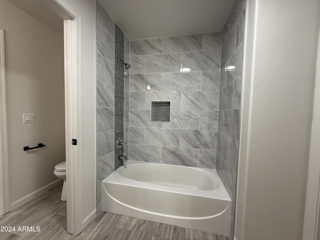 bathroom featuring tiled shower / bath and toilet