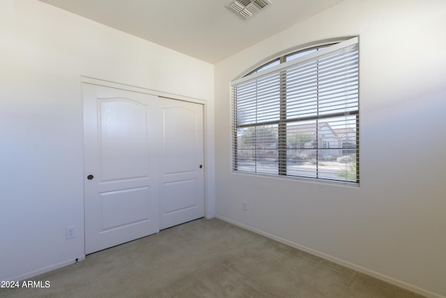 unfurnished bedroom featuring a closet, carpet floors, and multiple windows