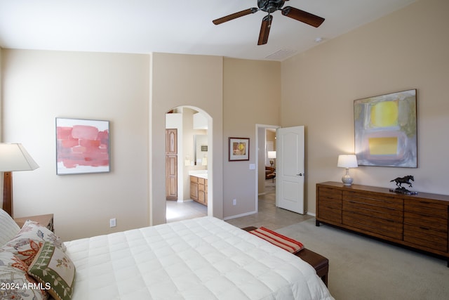 bedroom featuring high vaulted ceiling, light colored carpet, ensuite bath, and ceiling fan