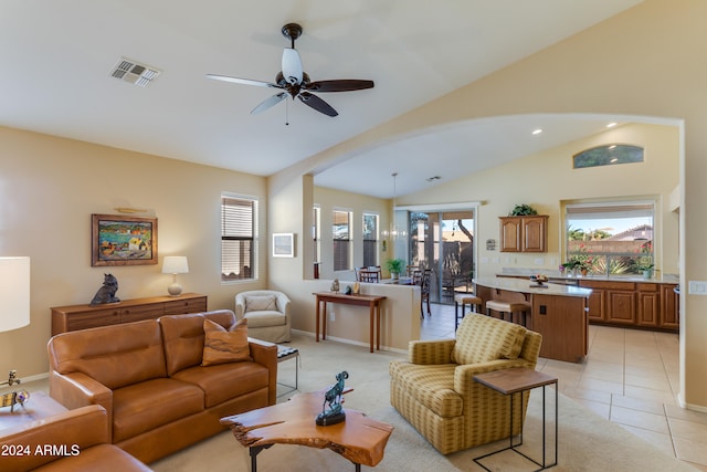 living room featuring ceiling fan, light tile patterned floors, and vaulted ceiling