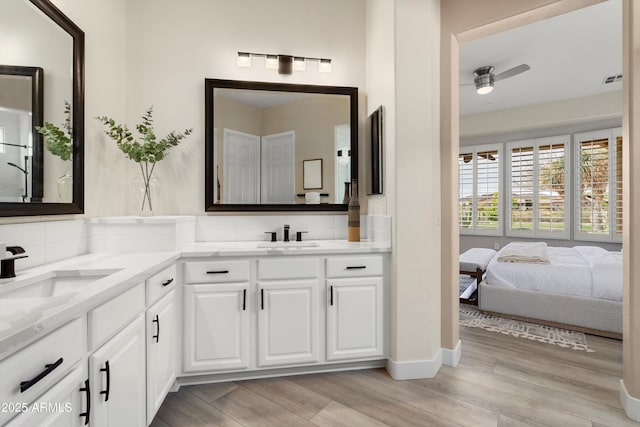 bathroom featuring double vanity, a sink, a ceiling fan, and wood finished floors