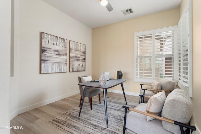 home office with a ceiling fan, visible vents, baseboards, and wood finished floors