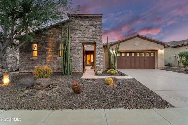 view of front of property with a garage, concrete driveway, stone siding, and stucco siding