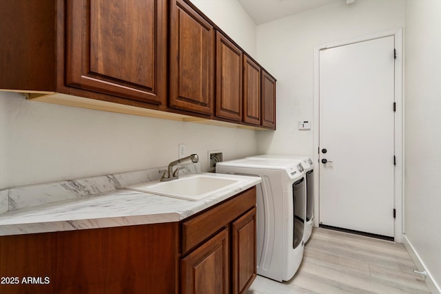 washroom with light wood-type flooring, independent washer and dryer, a sink, and cabinet space