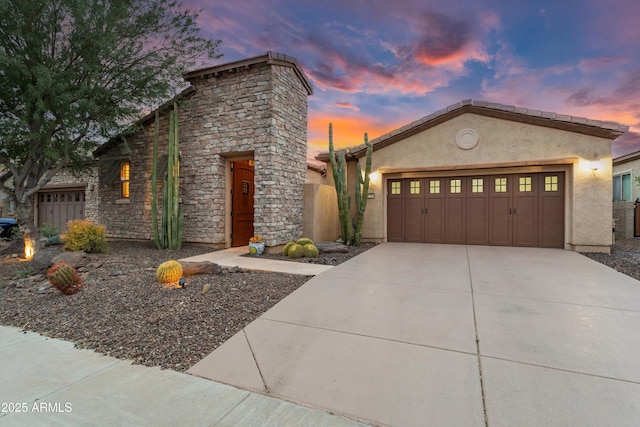 view of front of property featuring stone siding, an attached garage, concrete driveway, and stucco siding