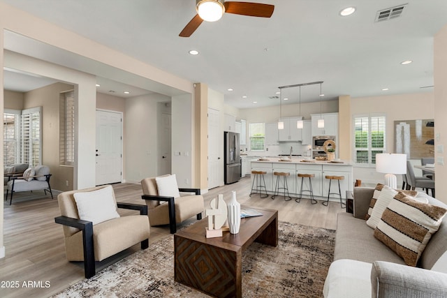 living area featuring light wood finished floors, baseboards, visible vents, and recessed lighting