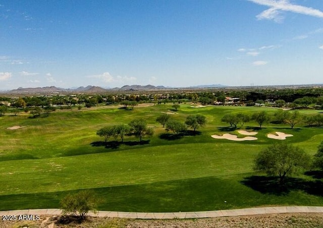 view of community featuring view of golf course, a yard, and a mountain view