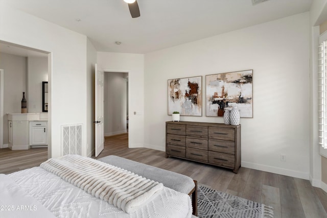 bedroom featuring baseboards, visible vents, wood finished floors, and ensuite bathroom