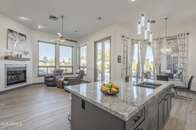 4915 N Greentree Dr, Litchfield Park, AZ 85340 - kitchen featuring sink, decorative light fixtures, dishwashing machine, light stone countertops, and a kitchen island with sink