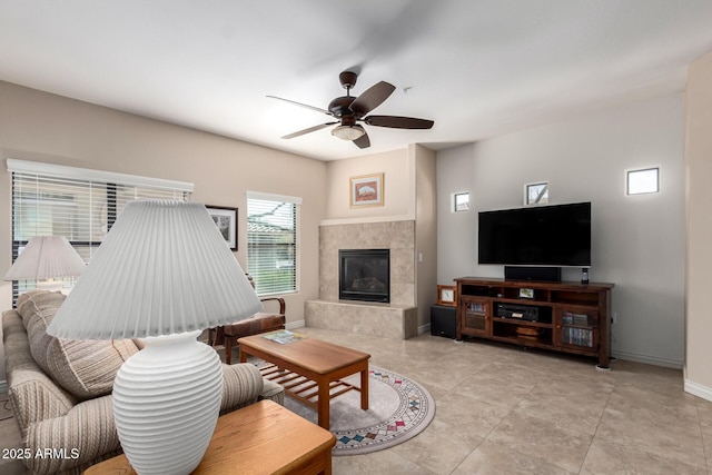 living room featuring ceiling fan, a tile fireplace, and light tile patterned floors