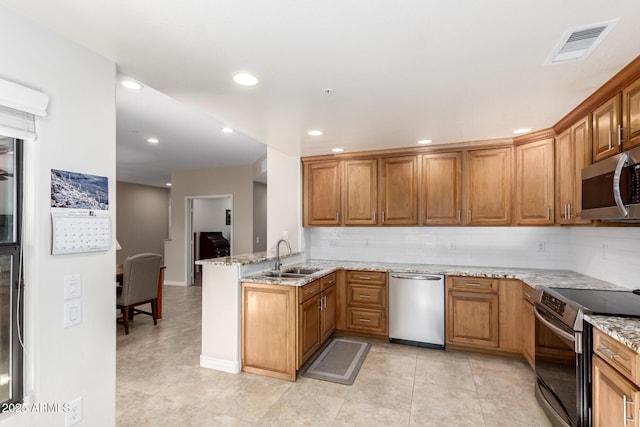 kitchen with sink, light stone counters, kitchen peninsula, stainless steel appliances, and backsplash